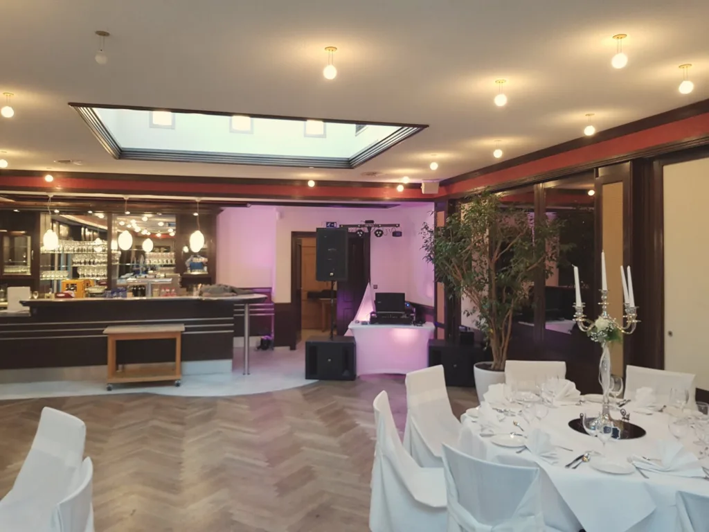 Festlich eingedeckter Saal mit DJ-Technik und Lichtakzenten