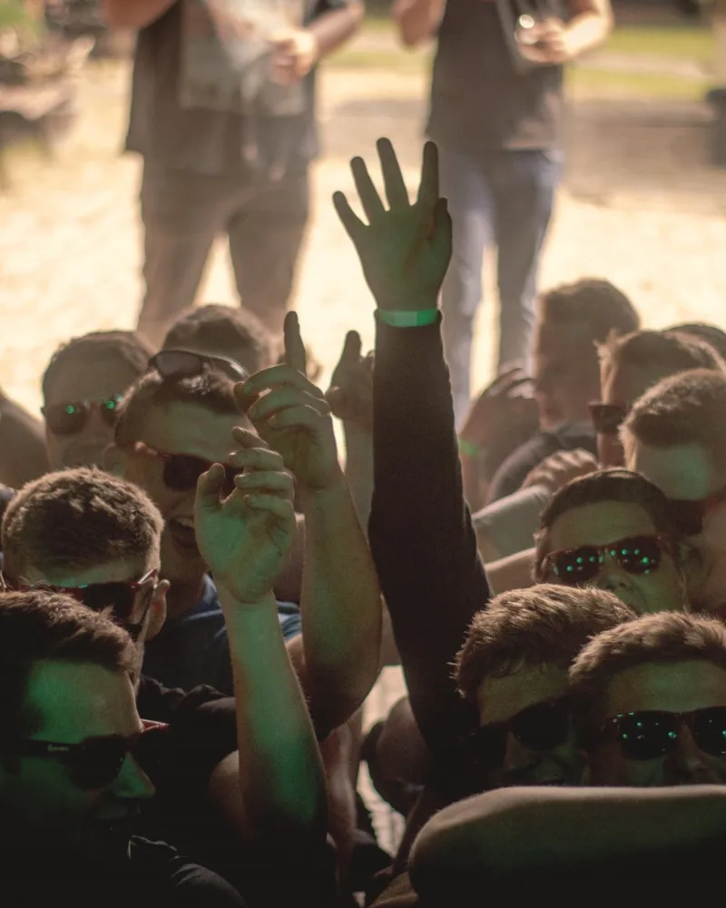 Gäste feiern mit erhobenen Armen vor dem DJ-Pult
